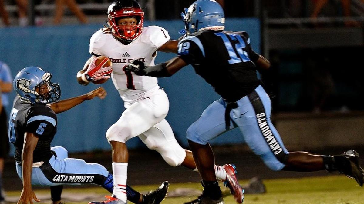 Middle Creek's Johnathan Spencer (1) runs through Panther Creek's Diamante Taylor (5) and Kenneth Edwards (12)during the football game on Friday, September 18, 2015 in Cary.