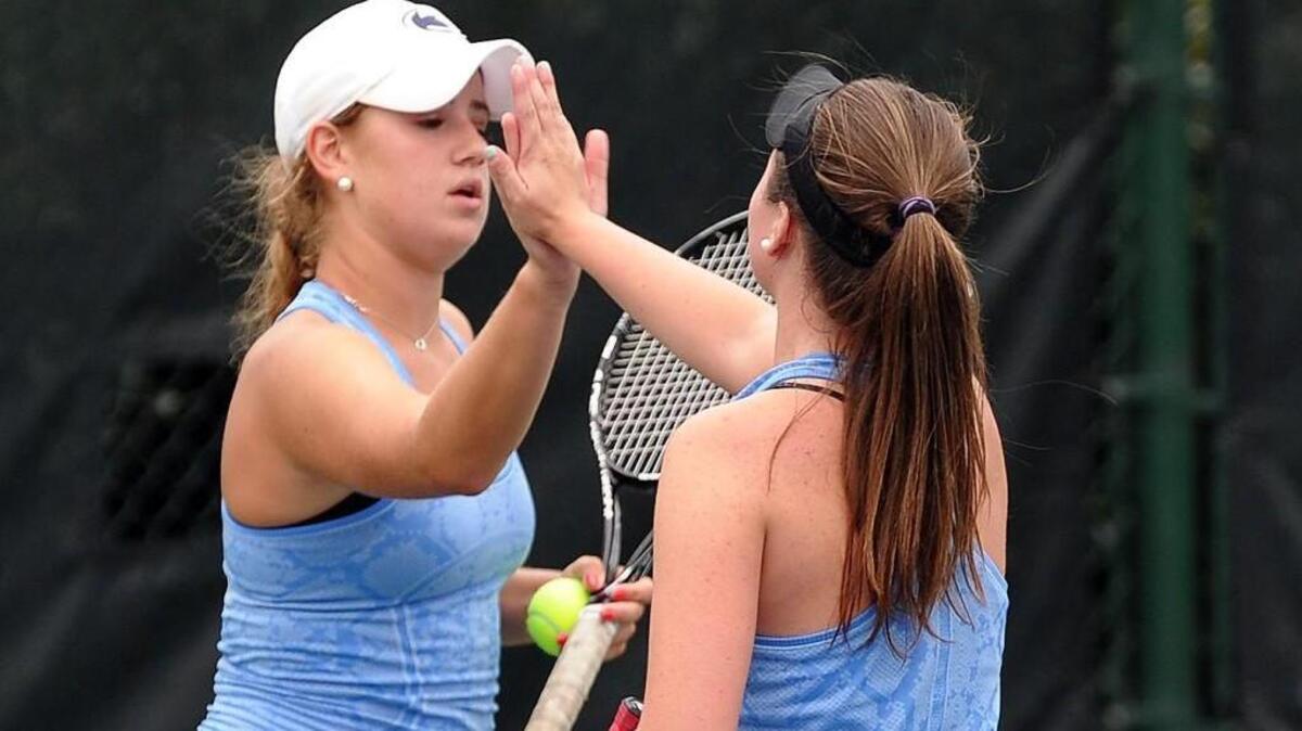 Panther Creek's Sammi Smith (left) and doubles partner Jordan Strickland high-five after winning a point during the girls tennis match against Green Hope on Thursday, September 24, 2015 in Cary.