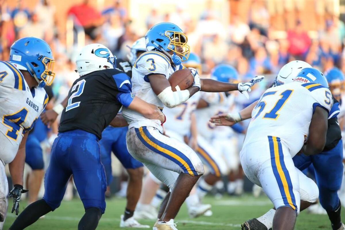 Garner's Daiveon Carrington ( 3) gains yardage as Clayton's Josh Collins ( 2) holds on during the football game with the Clayton Comets high school and the Garner Trojans high school in Clayton N.C. on August 18, 2017. won the game Clayton won the game 35-14.