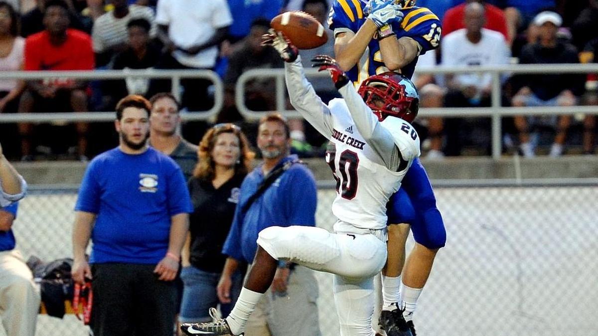 Middle Creek’s Darian Fogg (20) breaks up a pass intended for Garner's Justin Gahrmann (12) during the football game on Friday, September 4, 2015 in Garner. The two schools are in the same conference in the first NCHSAA realignment draft.