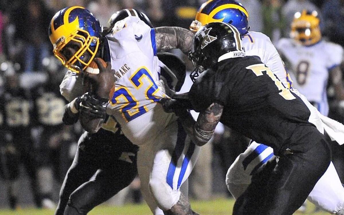 East Wake's Mikekale Engles (22) runs for the tough yardage while grappled by Knightdale's Jaelen Williams (7). The Knightdale Knights took on the East Wake Warriors in a football game in Knightdale, N.C. on Friday October 30, 2015.