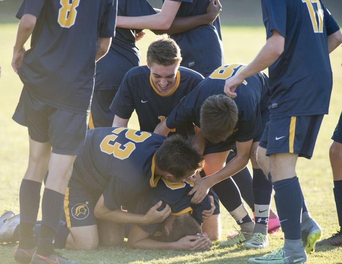 North Raleigh Christian players surround teammate Jake Strasser(19) after winning the 3A NCISAA State Soccer Championship between North Raleigh Christian Academy and Wesleyan Christian Academy that took place at Wesleyan Christian Academy on October 29, 2016 in High Point, North Carolina. North Raleigh Christian Academy comes from behind to defeat Wesleyan Christian Academy 3-1 in OT.