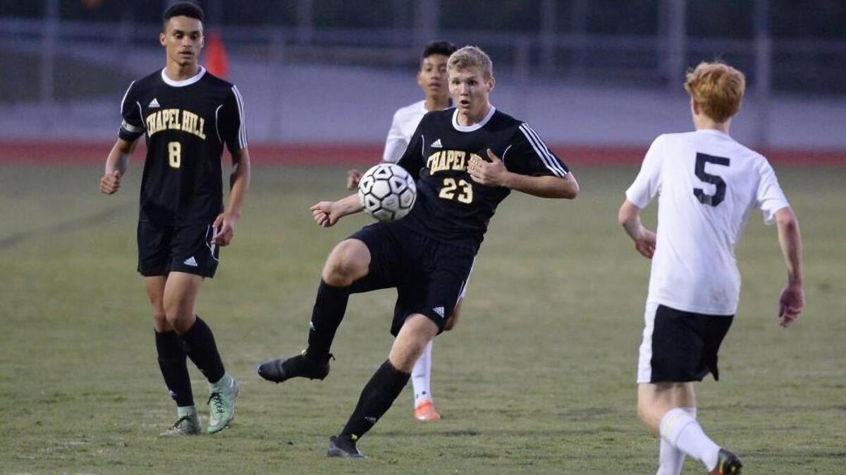Justin Mecham (23) of Chapel Hill passes the ball between Seth Maile (5) and Frank Orellana, second from left, of Cedar Ridge with assistance from his teammate Paul McLaughlin (8). The Cedar Ridge Red Wolves played the Chapel Hill Tigers in a boys soccer game that took place in Hillsborough, N.C. on Wednesday, October 12, 2016. Chapel Hill won 5-1.