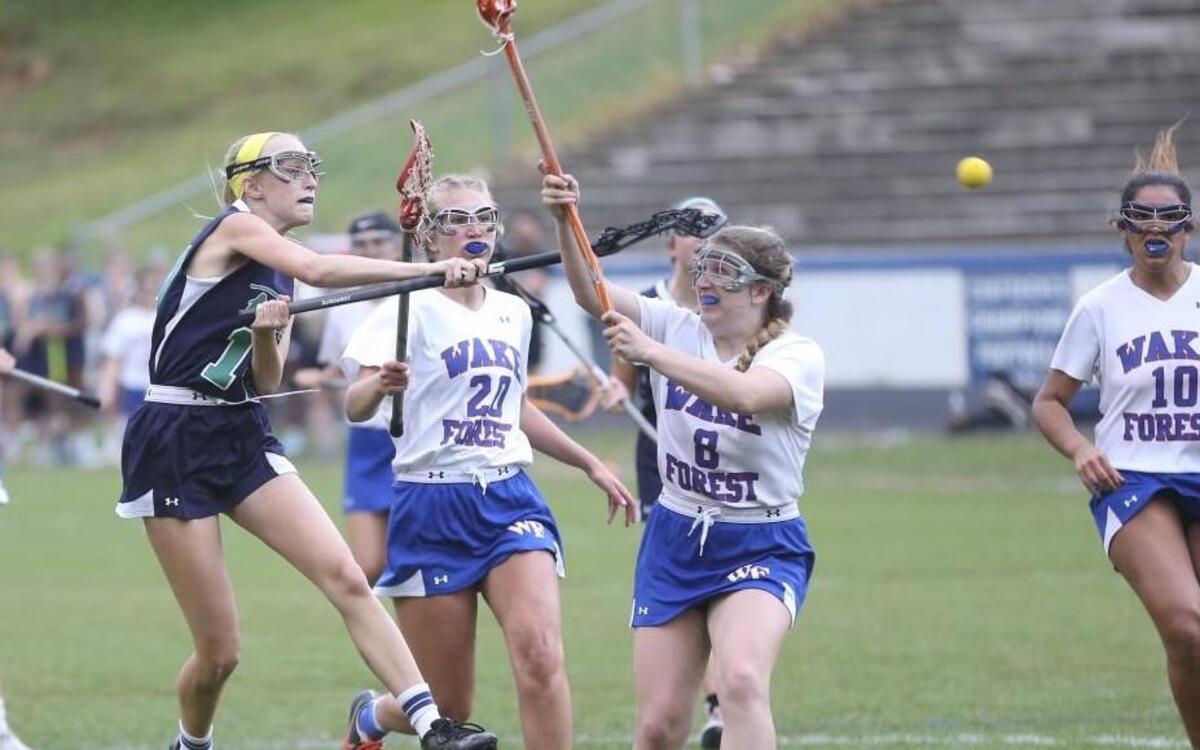 Leesville Road's Tyler Mae Stempien (14) launches a shot on goal as Wake Forest's Margaret Bautista (8) tries to stop the play. Coverage from the girls lacrosse game between the Wake Forest Cougars and the Leesville Road Pride played in Wake Forest, N.C. on Wednesday, April 19, 2017. Leesville Road defeated Wake Forest 7-4.