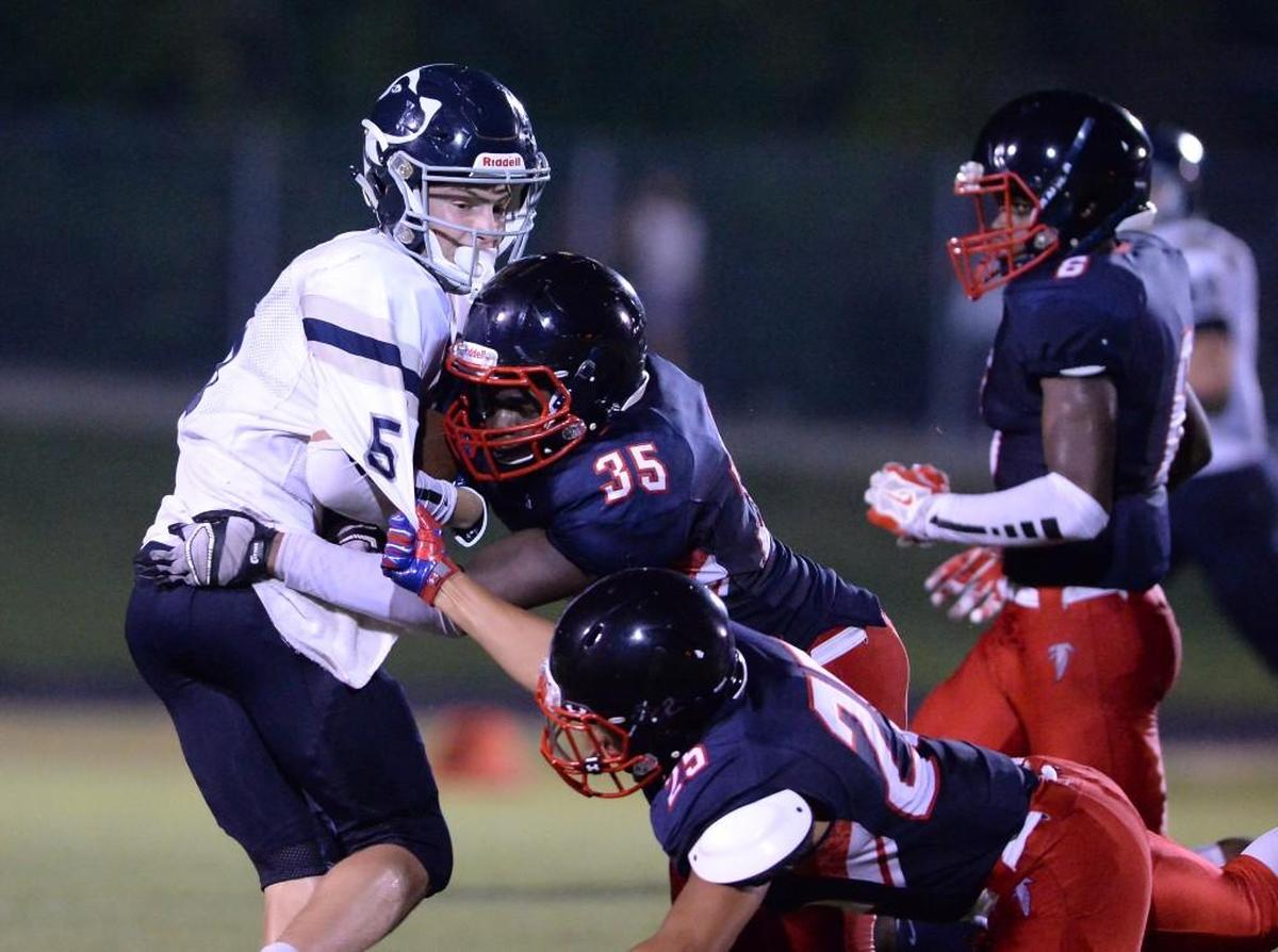Thayer Thomas (5) of Heritage moves the ball against a tackle from Tristan Edmond (35) and Oshay Yglesias (25) of Jordan. The Jordan Falcons played the Heritage Huskies in a football game that took place in Durham, N.C. on Friday, September 9, 2016. Heritage won 32-17.
