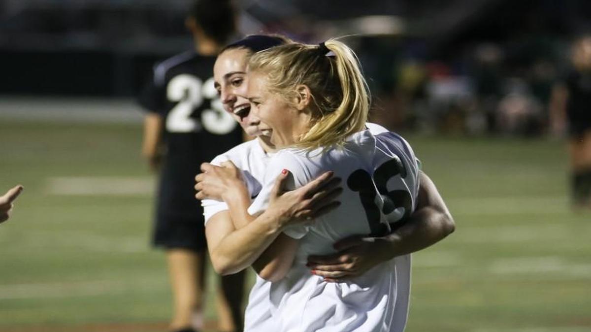 Cardinal Gibbons forward Emmy Duerr (15) gets hugged by teammate Caroline Goudy, left, after Duerr's late goal during East Chapel Hill's soccer game at Cardinal Gibbons on Monday, April 10, 2017. Cardinal Gibbons won the game 7-2.