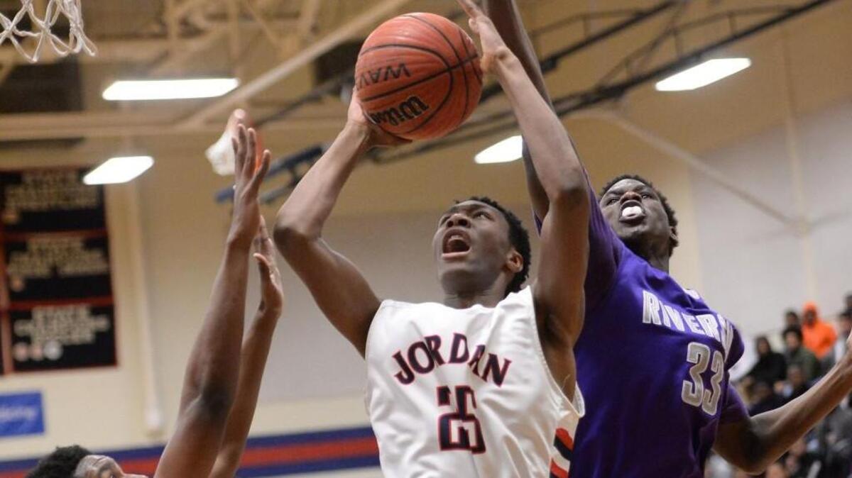 Jaylen Richard (25) of Jordan drives to the basket against Andrew Freeman, left, and Devin Farmer (33) of Riverside. The Jordan Falcons played the Riverside Pirates in a boys basketball game that took place in Durham, N.C. on Friday, February 5, 2016. Jordan won 76-63.