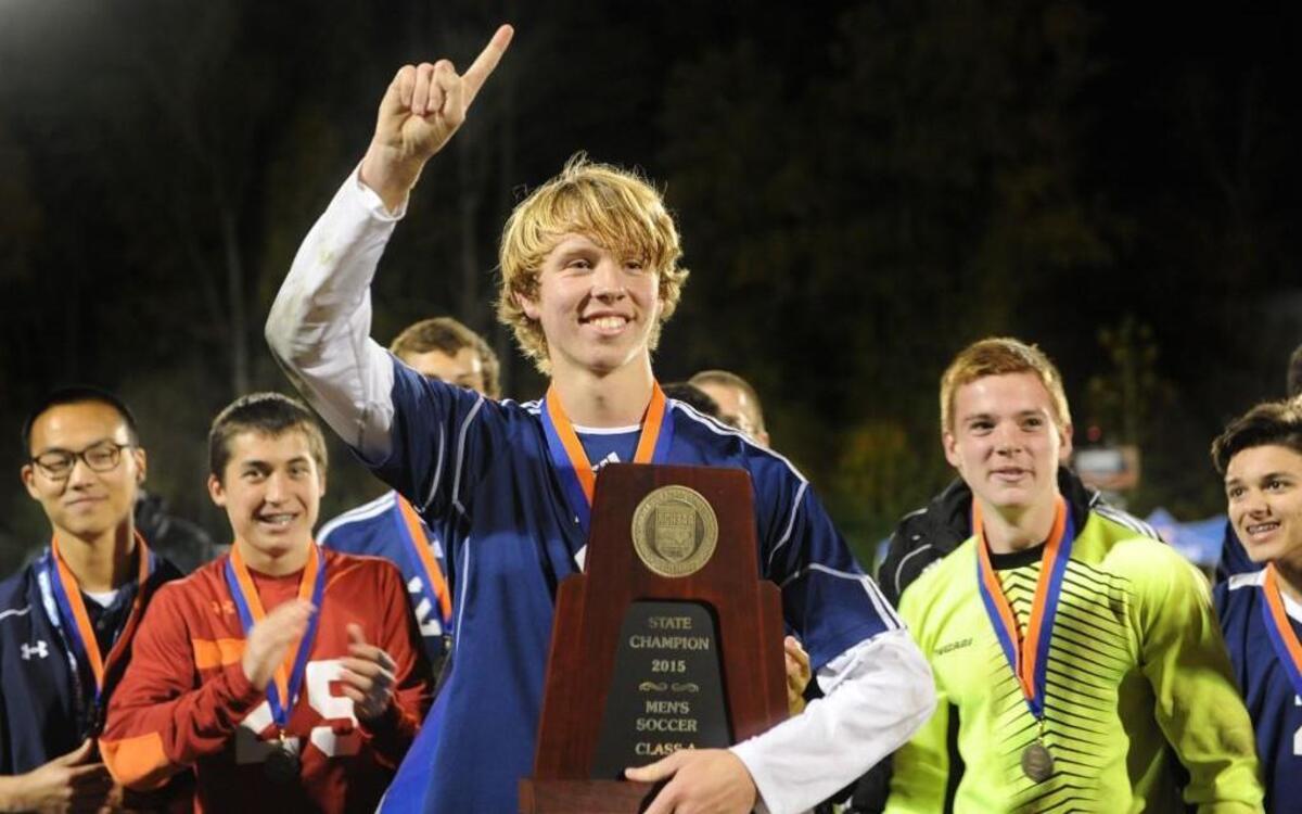 Nick Hughes accepts the Championship trophy on behalf of Franlkin Academy in the win over Commuity School of Davidson after the NCHSAA 1A boys soccer championship game, which was played on Saturday, November 21, 2015 in Raleigh. Franklin Academy won 3-1.