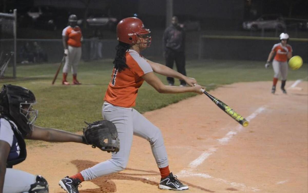 J'Naya Ephraim, center, of Southern hits the ball in front of Hillside's Joydan Parker, left. The Hillside Hornets played the Southern Durham Spartans in a softball game that took place in Durham, N.C. on Thursday, March 9 2017. Southern Durham won 30-20.
