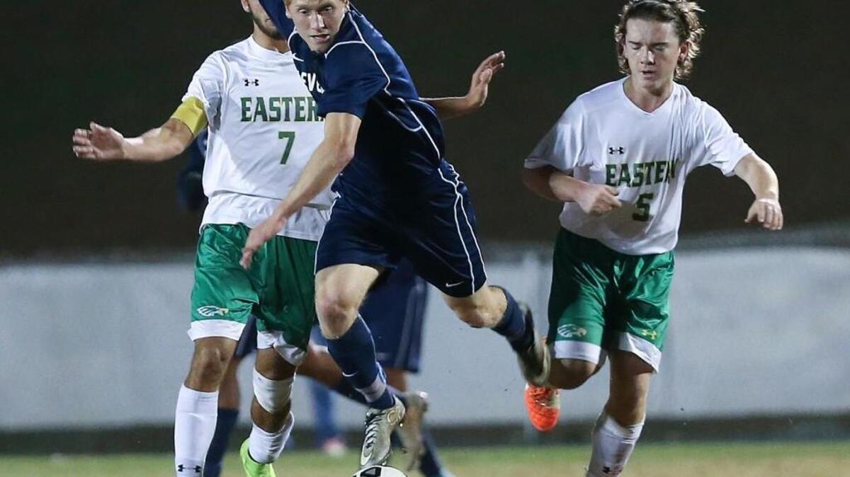 Cleveland's Tanner Costine (5) weaves his way through Eastern Alamance defenders Cole Burton (7) and Nic Jeffers (5). Coverage of 3rd round play in the 3A NCHSAA State Championship Soccer Tournament between the Cleveland Rams and Eastern Alamance Eagles played in Mebane N.C. on Wednesday, November 11, 2015. Eastern Alamance won 2-0.