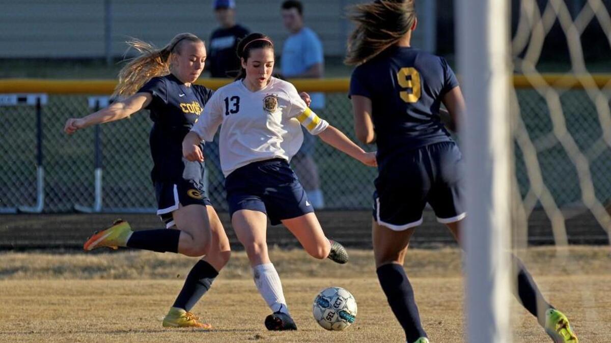 Eastern Wayne's Claire Molloy (13) kicking the ball as Goldsboro's Hannah Williamson (20) trails and Goldsboro's Ja'Quiera Braswell (9) defends during the Goldsboro High School girl's soccer game against Eastern Wayne High School in Goldsboro, N.C. on Monday, March 20, 2017.