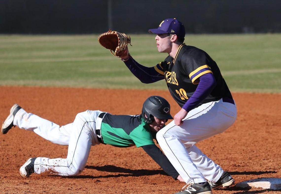 Cardinal Gibbon's Eric Farley (7) dives back to first as Riverside's Chris Crabtree (20) waits on the ball during the Riverside Pirates high school baseball game with the Cardinal Gibbons Crusaders high school , March 15, 2017, in Raleigh , N.C. Cardinal Gibbons won the game 6-1.
