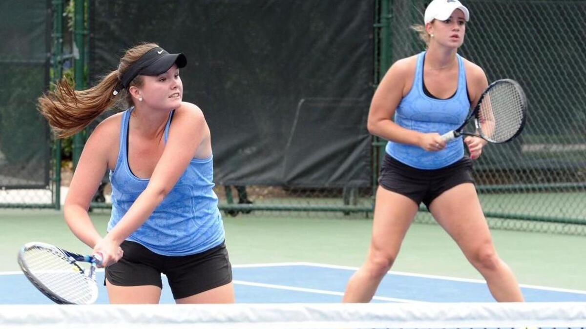 Panther Creek's Jordan Strickland (left) plays the net while doubles partner Sammi Smith looks on during the girls tennis match against Green Hope on Thursday, September 24, 2015 in Cary.