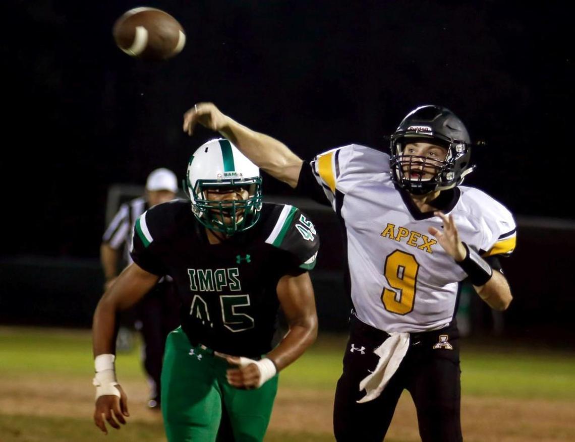 Apex quarterback Duke Fruehauf (9) throws a pass as Cary defender Davin Vann (45) chases during Apex’s football game at Cary on Friday, September 16, 2016. Apex won the game 35-34.