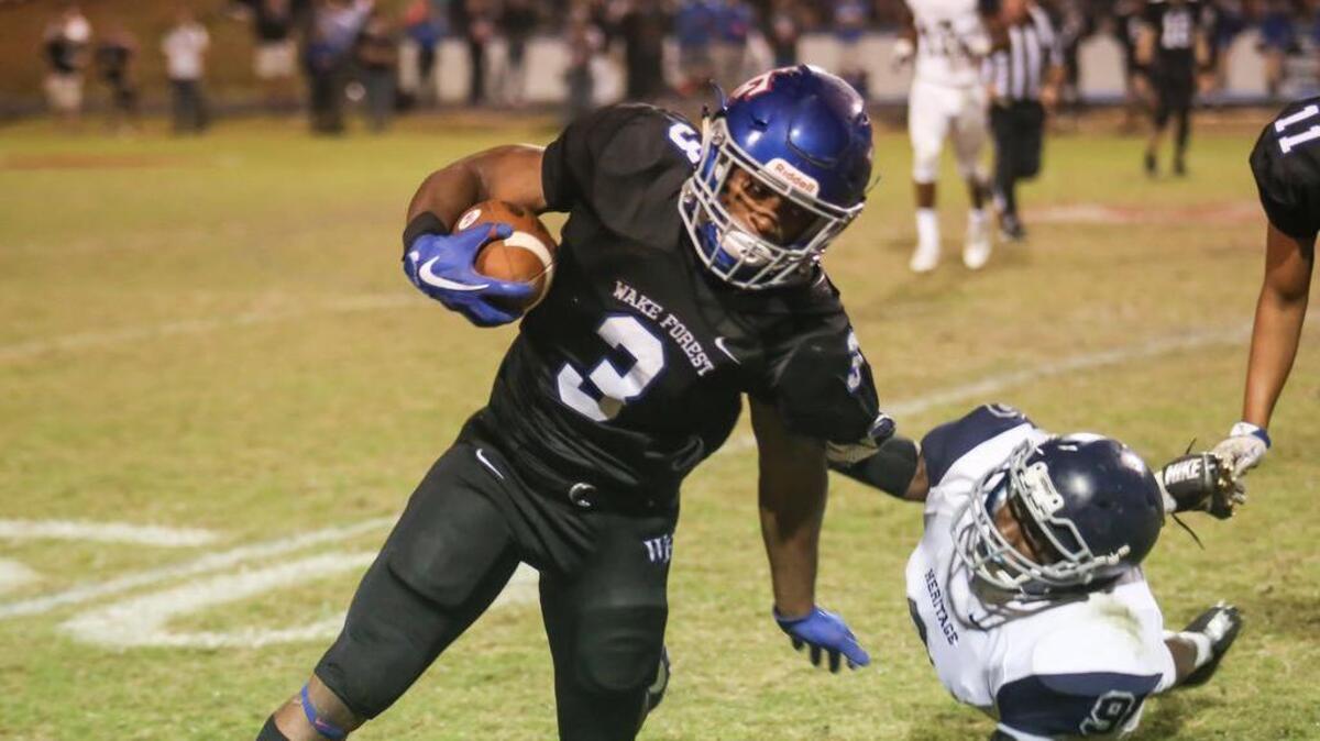 Heritage defender Joshua Coleman (9) dives as he grabs the jersey of Wake Forest running back Devon Lawrence (3) on an edge run. The Heritage Huskies visited the Wake Forest Cougars in a high school football game on Nov. 3, 2017.