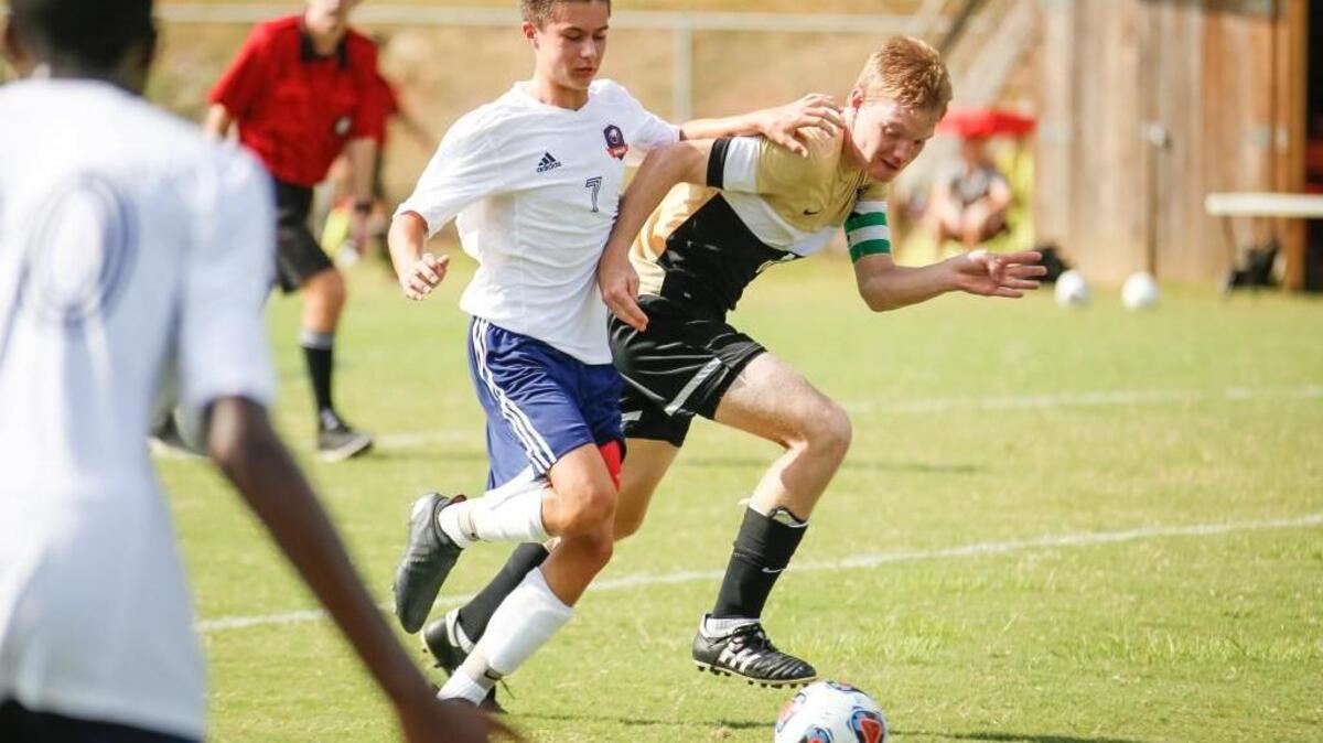 Grace Christian's Spencer Keiswitter (7) dribbles upfield while he tries to hold off Trinity Academy's Jo Maurais (10) during Trinity Academy Raleigh's soccer game at Grace Christian on Tuesday, August 30, 2016. Grace Christian won the game 3-2 in extra time.