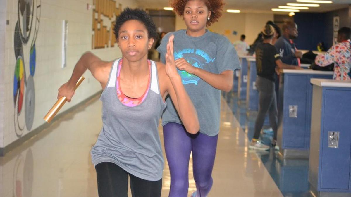 Southeast Raleigh’s Saidah Hardwick, front, takes a handoff from Asya Macon during a recent practice. Because of the weather conditions, the teams have to practice indoors.