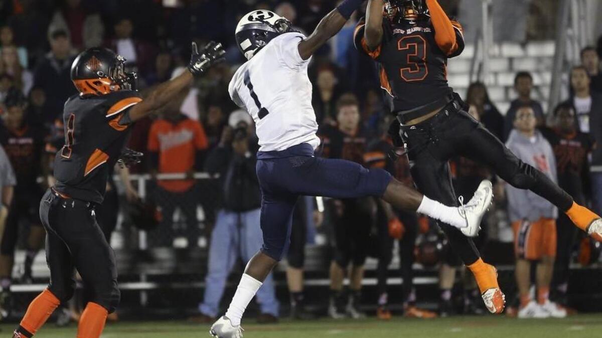 Hillside's Marcus Krah (1) tries to break up this interception late in the second quarter but New Hanover's Keaun Wallace (3) is able to make the pick.