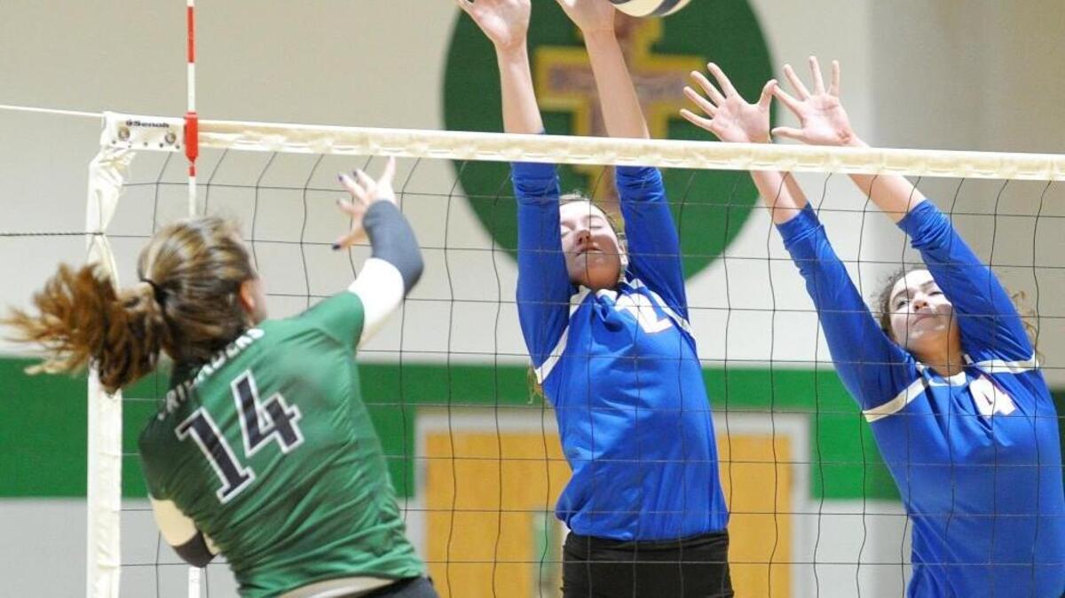 Cardinal Gibbons' Delaney Hahn (14) kills a ball as Person's Hailey Long (12) and Avery Bowman (4) try to block during the volleyball match, which was played in Raleigh on Tuesday, October 11, 2016.