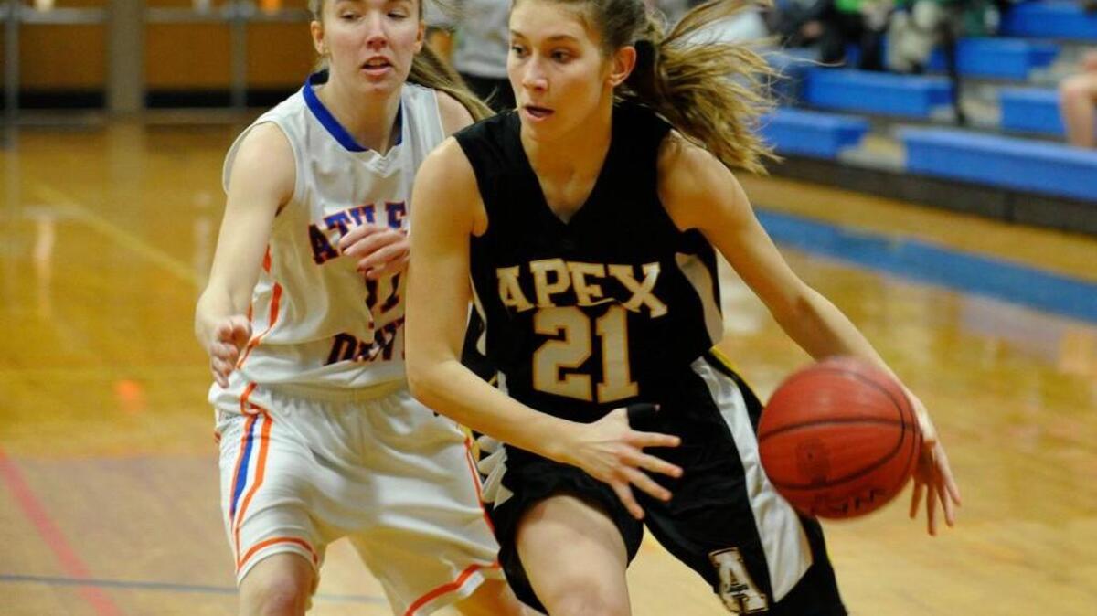 Apex's Elle Hepburn (21) drives to the basket past Athens Drive's Gabby Respess (11). The Apex Cougars and the Athens Drive Jaguars girls basketball game was played in Raleigh on Friday, January 30, 2015. Athens Drive won 55-54.