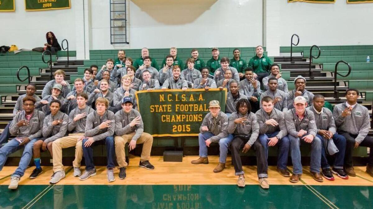 The 2015 Ravenscroft football team pose for a photo with their state championship rings after a home boys’ basketball game on Wednesday night. They defeated Christ School in November to become NCISAA 2A champions.