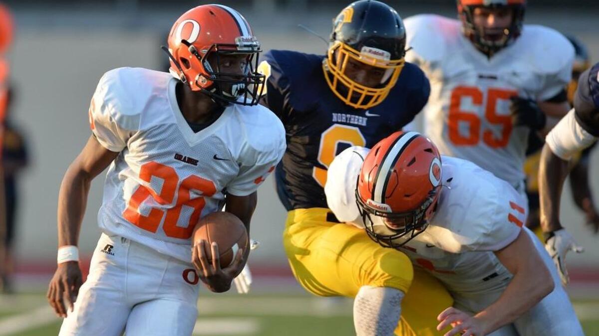 Morgan Paschal (26) of Orange carries the ball while his teammate Payton Wilson (11) protects him from being tackled by Thomas Gongs, center, of Northern. The Northern Knights played the Orange Panthers in a football game that took place at the Durham County Memorial Stadium in Durham, N.C. on Friday, August 26, 2016. Orange won 21-13.