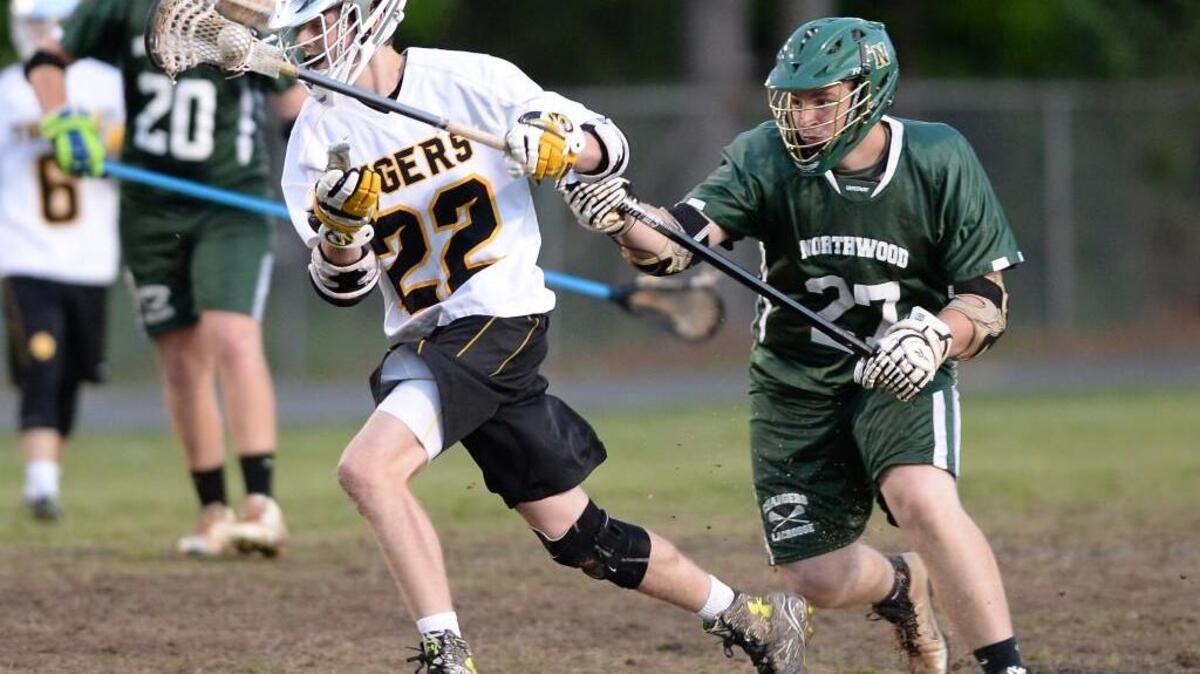 T.J. Malloy (22) of Chapel Hill moves the ball up field against the pursuit of Jordan Dalton (27) of Northwood. The Chapel Hill Tigers played the Northwood Chargers in a boys lacrosse game that took place in Chapel Hill, N.C. on Saturday, May 7, 2016. Chapel Hill won 11-5.