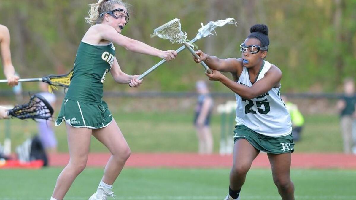 Jordan Lappin, left, of Cardinal Gibbons scores a goal against the defense from Lydia Carbuccia, right, of Durham Academy. The Durham Academy Cavaliers played the Cardinal Gibbons Crusaders in a girls lacrosse game that took place in Durham, N.C. on Monday, April 11, 2016. Cardinal Gibbons won 18-8.