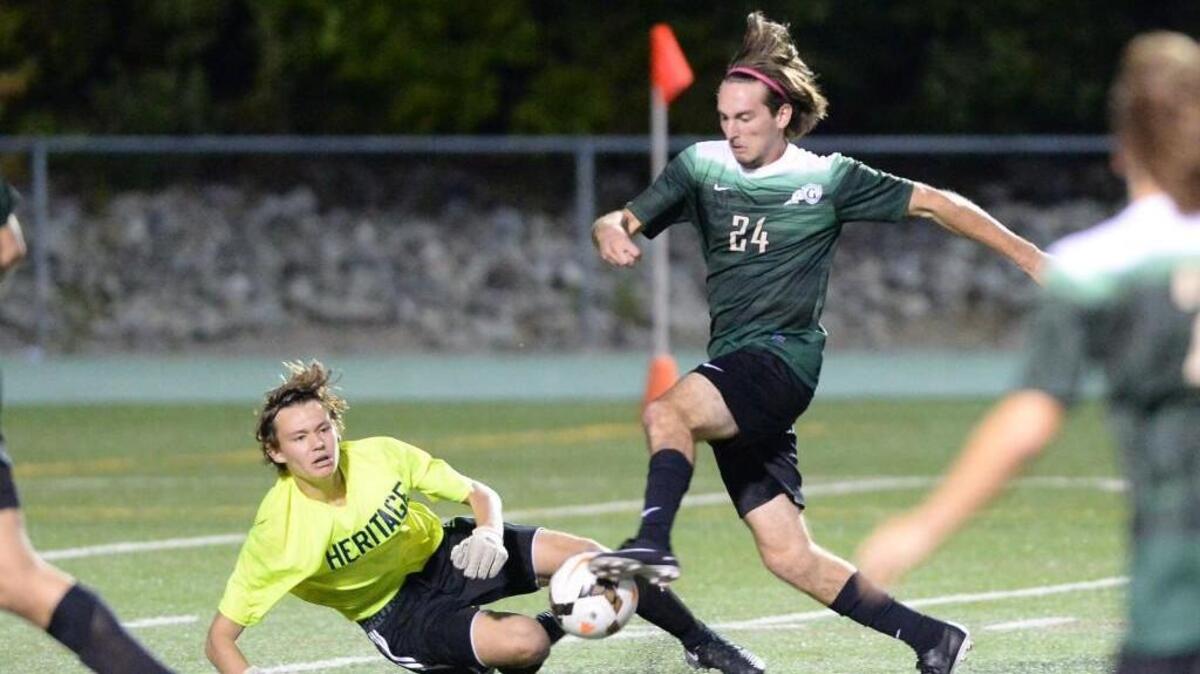 Nicholas Brassington (24) of Cardinal Gibbons dribbles past Heritage's goal keeper Ashton Ferrante, left, to score the first goal for the Crusaders. The Heritage Huskies visited the Cardinal Gibbons Crusaders in the Wake County Cup championship high school soccer game on Sept. 23, 2017.