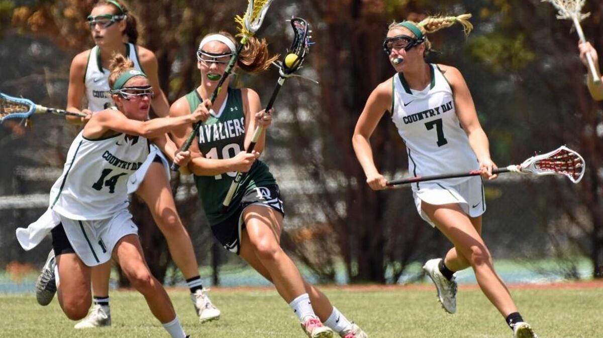 Durham Academy’s Madison Dunk (center) is trapped between Charlotte Country Day defenders Riley Harrison (left) and Sally Dowd (right) during the second half of the NCISAA state girls lacrosse championship game at Country Day’s Belk Stadium on Saturday, May 21, 2016. Country Day beat Durham Academy 18-2 to win its fourth straight state title. CREDIT: Bill Kiser