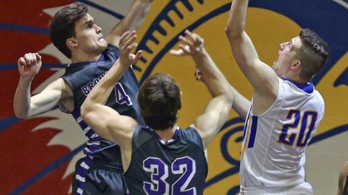Garner's Nick Kuhns (20) scores the opening basket over Broughton's Aaron Gottfried (4) and the Trojans never look back. Coverage from the 2nd round of the Boys NCHSAA 4A basketball playoffs between the Garner High Trojans and the Broughton High Capitals played in Garner, N.C. on Thursday, February 25, 2016. Garner advanced to the 3rd round defeating Broughton 85-71.