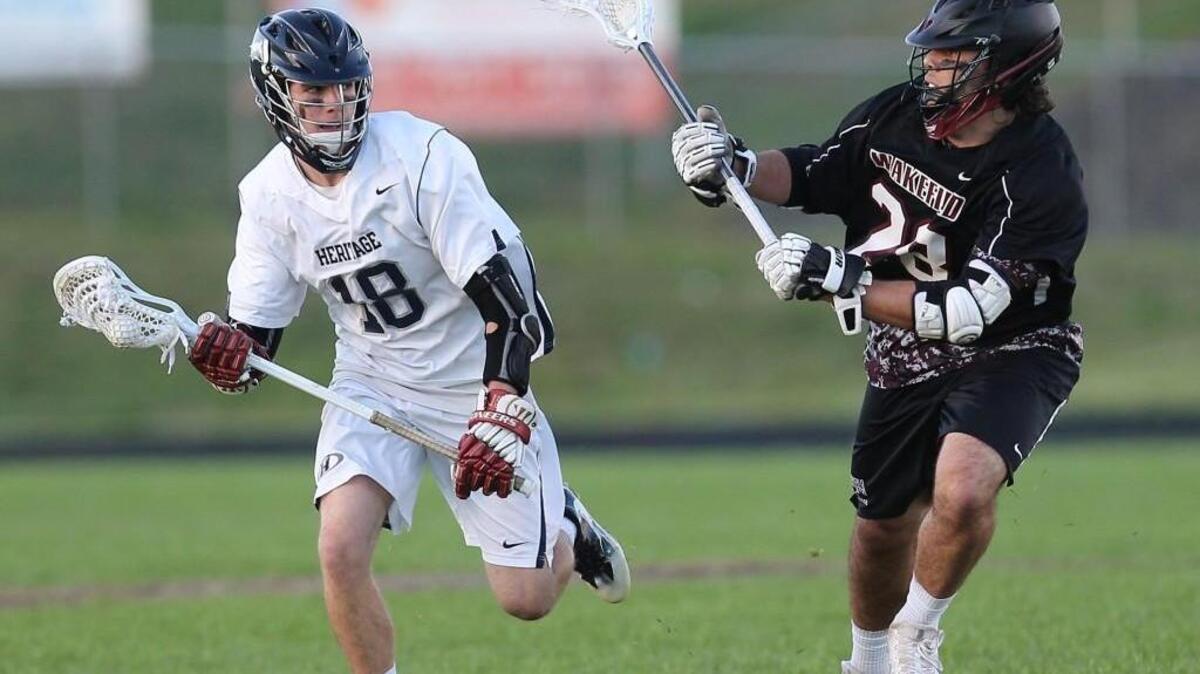 Wakefield's Jarod Goss (28) defends Heritage's Ryan Cornell (18) during the Wakefield Wolverines high school lacrosse game with the Heritage Huskie's high school on April 4, 2017. Heritage won the game 17-15.