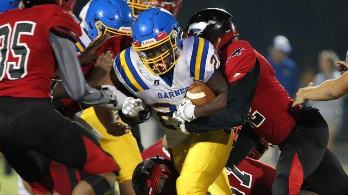 Garner's Joshua Wilson (20) is brought down by Middle Creek's Darnell Jones (12). The Garner Trojans visited the Middle Creek Mustangs in a high school football game on Nov. 3, 2017.