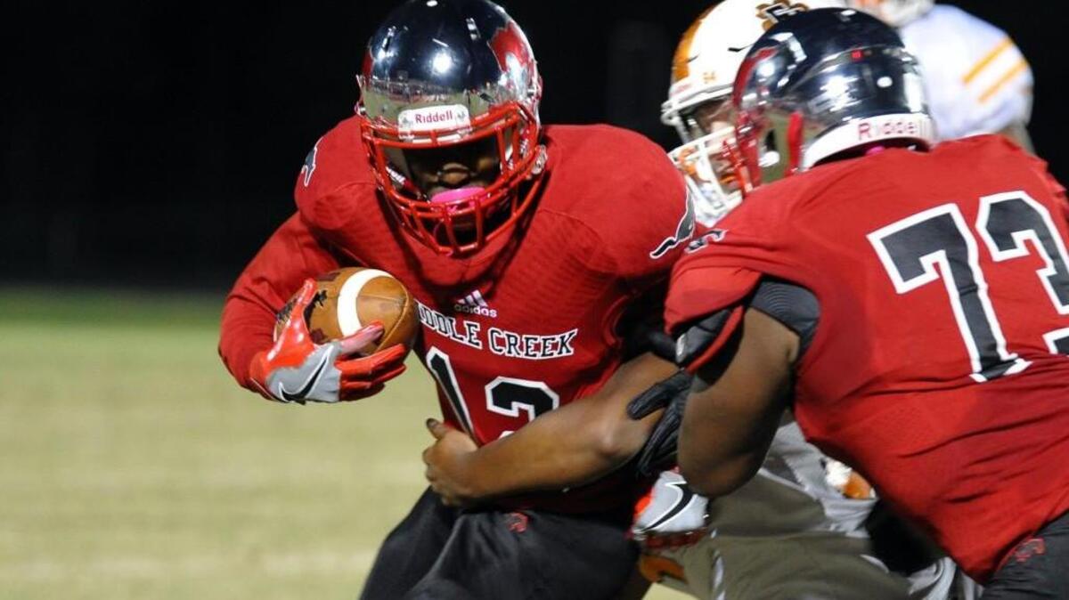 Middle Creek's Robert Robinson (73) blocks for Shammond Hicks (12) against Fuquay-Varina during the football game, which was played in Apex on Friday, October 14, 2016. Middle Creek won 42-14.
