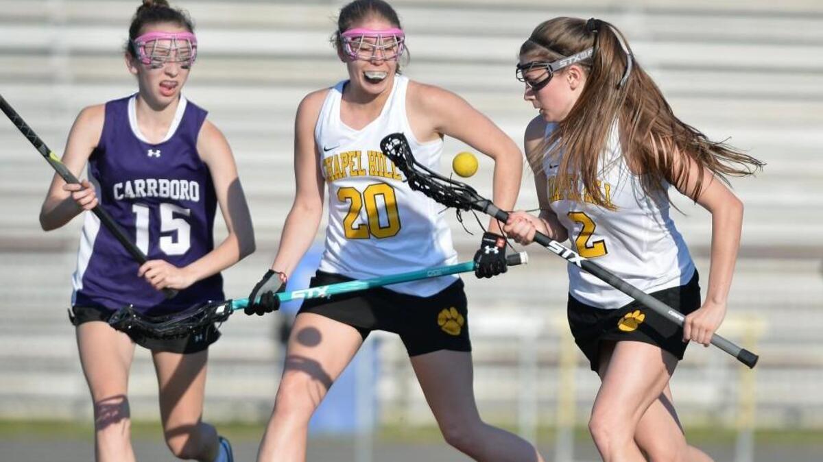 Paige Haskins (2) and Jane McMurry (20) of Chapel Hill win ball possession against Catherine Strong (15) of Carrboro. The Chapel Hill Tigers played the Carrboro Jaguars in Chapel Hill, N.C. on Tuesday, April 26, 2016. Chapel Hill won 14-4.