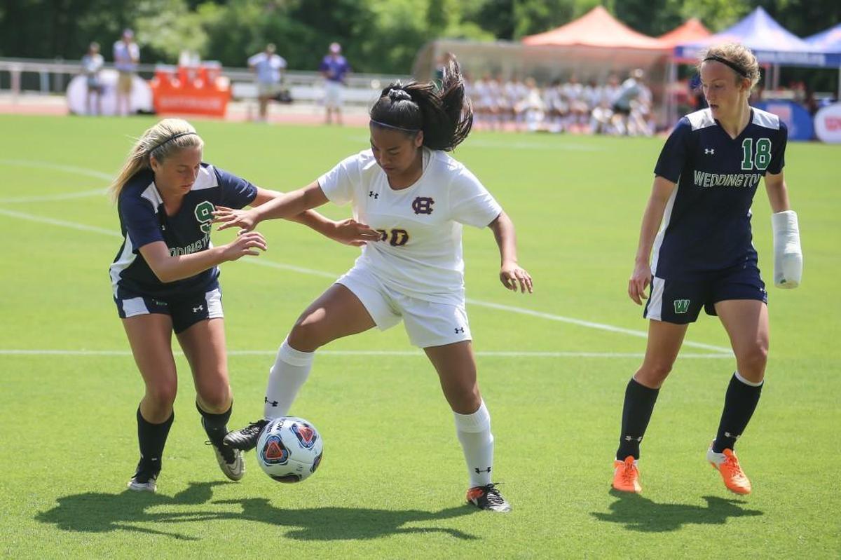 Corinth Holders' Anu Kane (10) dribbles between Weddington defenders Maddie Smith (9) and Faith Adams (18) during the NCHSAA 3A girls soccer state championship match between Corinth Holders and Weddington at NC State University on Saturday, May 27, 2017. Weddington won the game 1-0.
