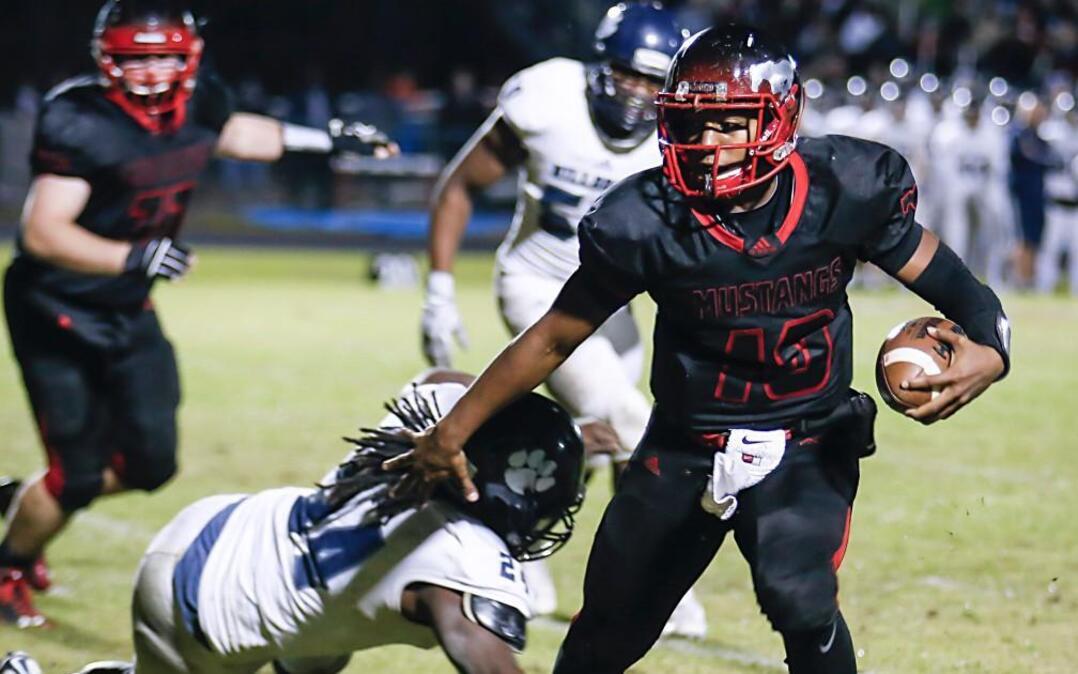 Middle Creek quarterback Dominique Shoffner (10) carries on a short run down to the goal line as Millbrook's Montavius Baker(24) tries to make the tackle during Millbrook's playoff football game at Middle Creek on Friday, November 20, 2015. Middle Creek won the game 35-14.