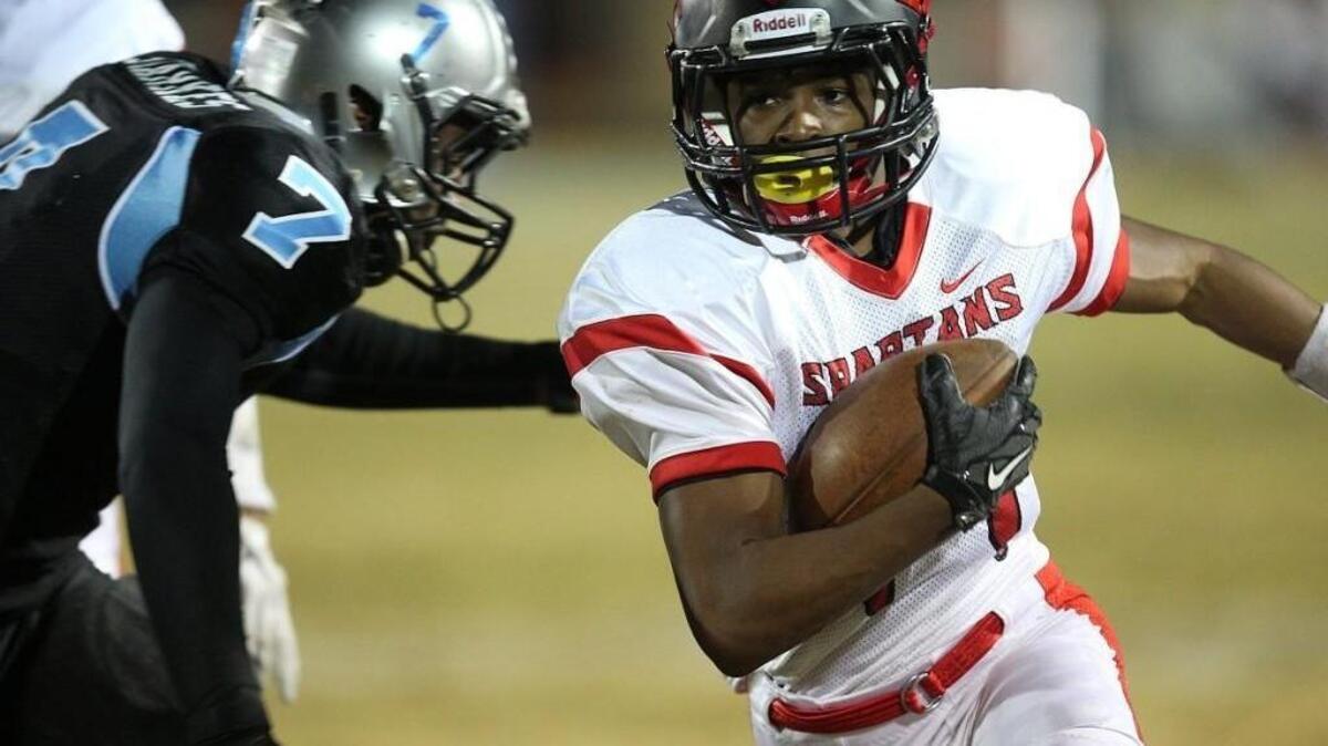Southern Durham's Jermaine Russell Jr. (14) runs by Cleveland's Delancey Starkes (7) during round 3 of the 3AA football NCHSA playoffs with Southern Durham High School football game against Cleveland High School, November 27, 2015, Clayton, N.C. Southern Durham leads at the half 12-7.