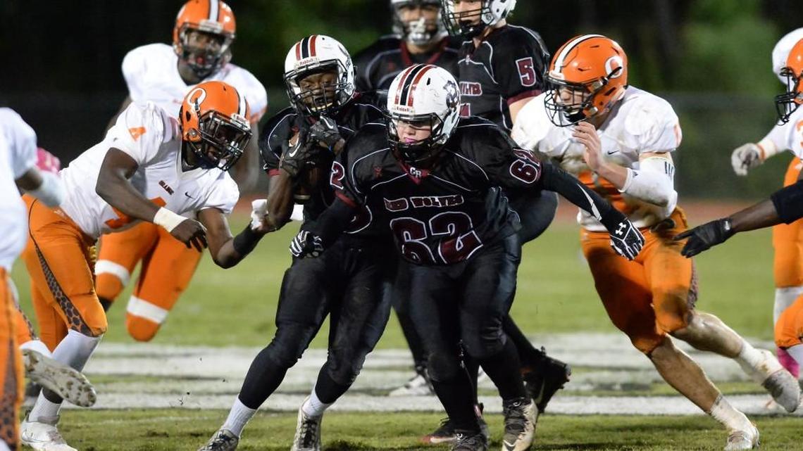 Shemar Miles, second from left, of Cedar Ridge carries the ball with help from his teammate Taylor Daniel, second from right against the defense from Devondrez Moore, left, and Payton Wilson, right, of Orange. The Cedar Ridge Red Wolves played the Orange Panthers in a football game that took place in Hillsborough, N.C. on Friday, October 14, 2016. Orange won 42-3.