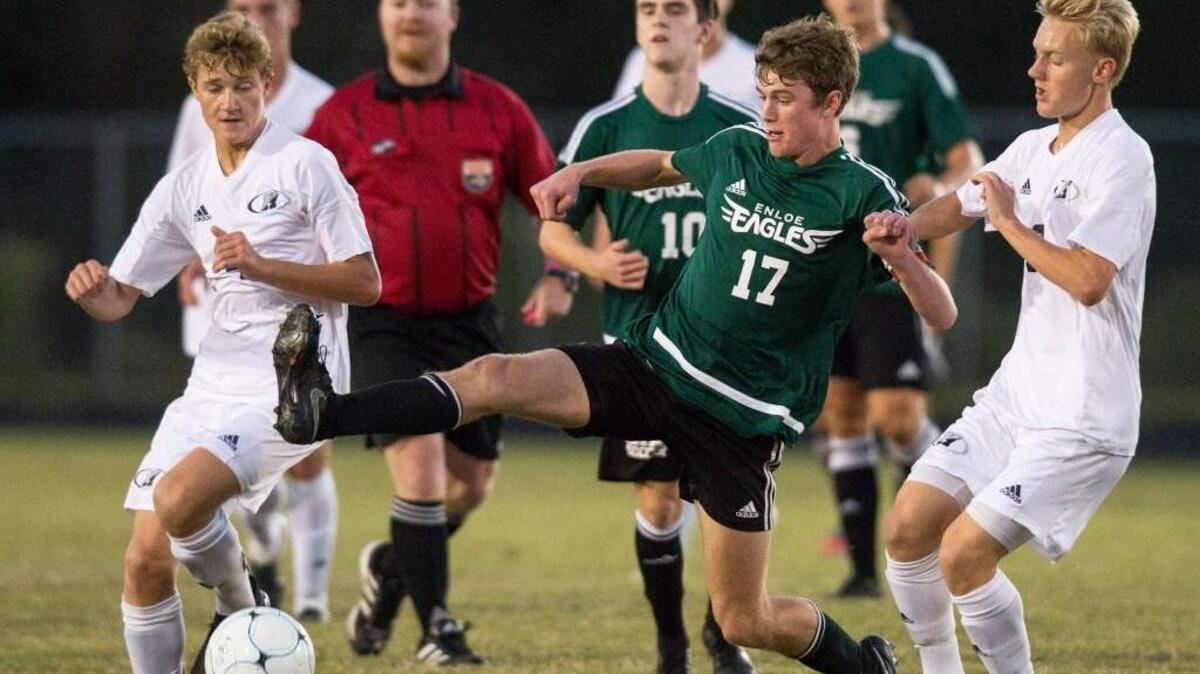 Enloe's Luke Buxton (17) reaches for the ball as Heritage’s Jacob Owczarzak, left, and Heritage’s Caleb Bratager, right, defend during a high school soccer game in Wake Forest, N.C. on Wednesday, Oct. 12, 2016.