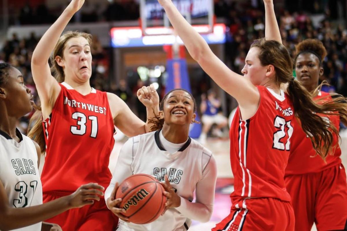Southeast Raleigh's Jada McMillian, center, drives as Northwest Guilford defenders Elizabeth Kitley (31) and Cayla King (21) converge during the NCHSAA 4A Girls Basketball State Championship game between Southeast Raleigh and Northwest Guilford in Raleigh on March 11, 2017. Northwest Guilford won the game 36-34.