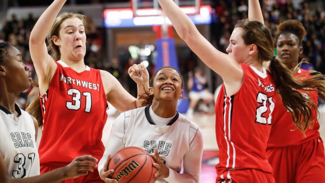 Southeast Raleigh's Jada McMillian, center, drives as Northwest Guilford defenders Elizabeth Kitley (31) and Cayla King (21) converge during the NCHSAA 4A Girls Basketball State Championship game between Southeast Raleigh and Northwest Guilford in Raleigh on March 11, 2017. Northwest Guilford won the game 36-34.