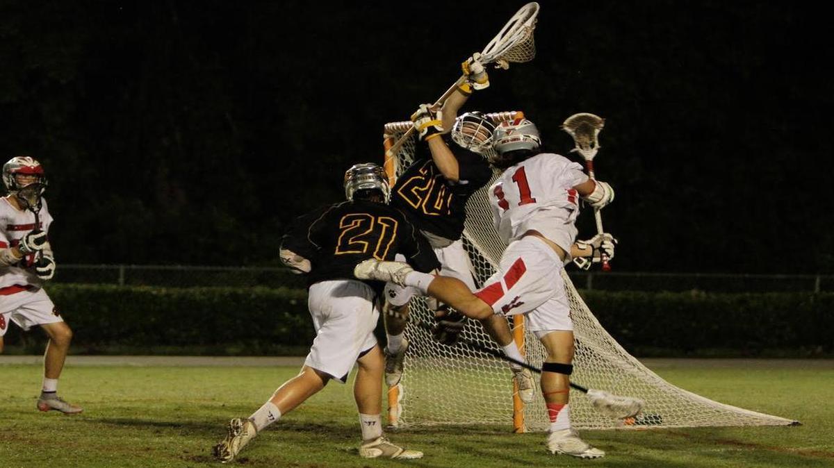 Chapel Hill goalkeeper Kyle Hornik (20) goes high to snare a shot by Jacksonville’s Logan Sullivan during Friday night’s NCHSAA third-round playoff game. Chapel Hill upset Jacksonville 11-10 on the Cardinals’ home field to advance to the NCHSAA 3A/2A/1A semifinals Tuesday, where the Tigers will face Carrboro.