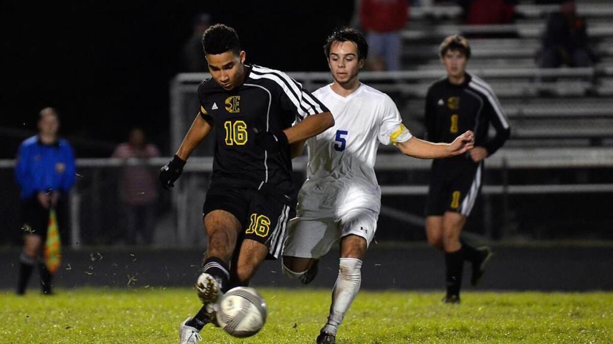 Enloe senior captain Yago Santos (16) moves the ball forward while defended by East Wake senior captain Johnny Odette (5) during their game in the second round of the NCHSAA 4A boys soccer playoffs in Wendell, N.C. Wednesday, Nov. 11, 2015.