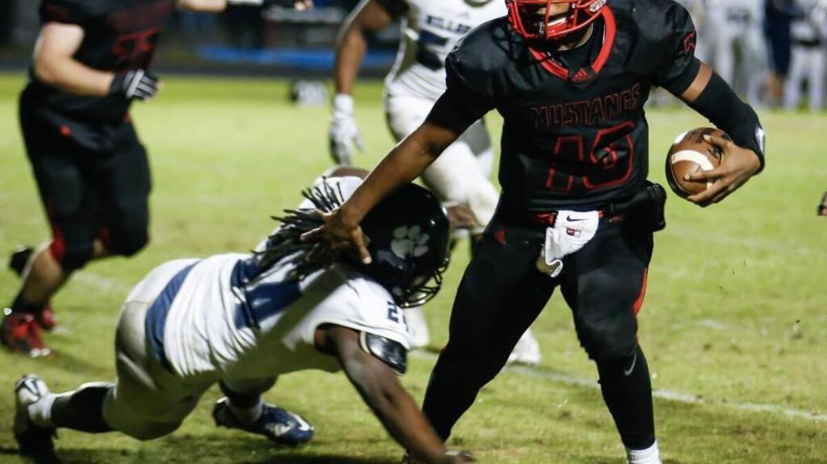 Middle Creek quarterback Dominique Shoffner (10) carries on a short run down to the goal line as Millbrook's Montavius Baker(24) tries to make the tackle during Millbrook's playoff football game at Middle Creek on Friday, November 20, 2015. Middle Creek won the game 35-14.