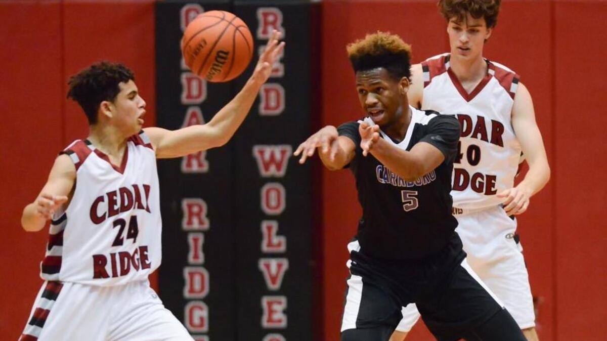 Ja'Ny Alston (5) of Carrboro passes the ball against Mekai Collins (24) and Isaiah Brown, right, of Cedar Ridge. The Cedar Ridge Red Wolves played the Carrboro Jaguars in a men basketball game that took place in Hillsborough, N.C. on Friday, December 2, 2016. Cedar Ridge won 65-36.