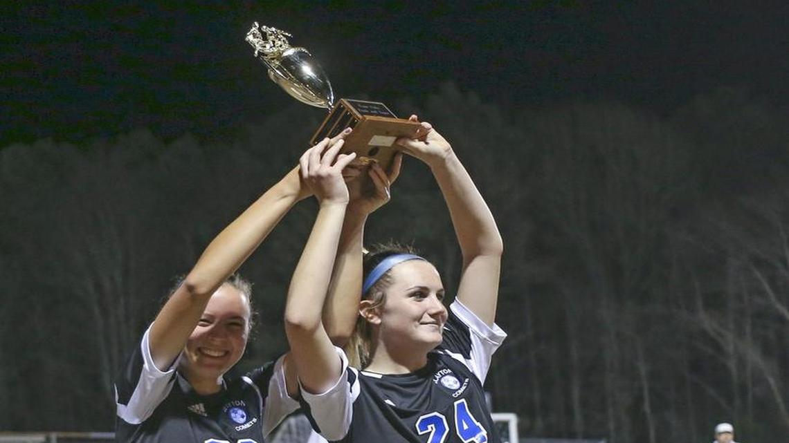 Clayton seniors Sophia Woznichak (20) and Kendall Gillespi (24) accept the Four Oaks Bank Cup championship trophy. Coverage from the Four Oaks Bank Cup Girls Soccer Tournament championship game between the Clayton Comets and the West Johnston Wildcats played in Smithfield, N.C. on Wednesday, March 1, 2017. Clayton defeated West Johnston 4-0 to win the championship.