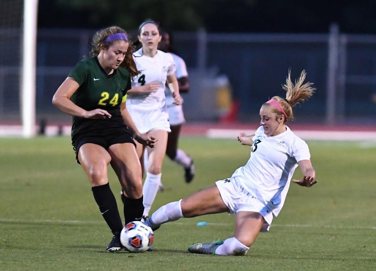Maggie Pierce, right, of Cardinal Gibbons slides for the ball against Elizabeth Neblett (24) of West Forsyth. The Cardinal Gibbons Crusaders played the West Forsyth Titans in a soccer game that took place in Raleigh, N.C. on Saturday, May 27 2017. West Forsyth won 4-3.