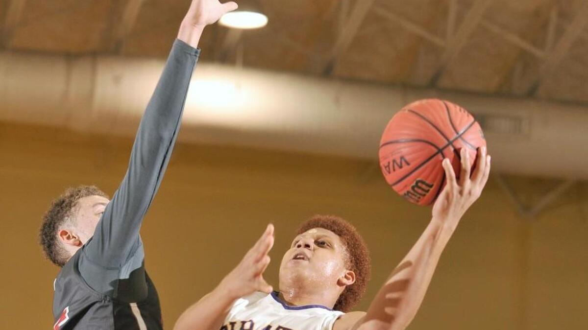 Khalil Bryant of Corinth Holders twists around Jacksonville’s Simon Martin to put up a shot in the Pirates’ second-round playoff win Thursday night.