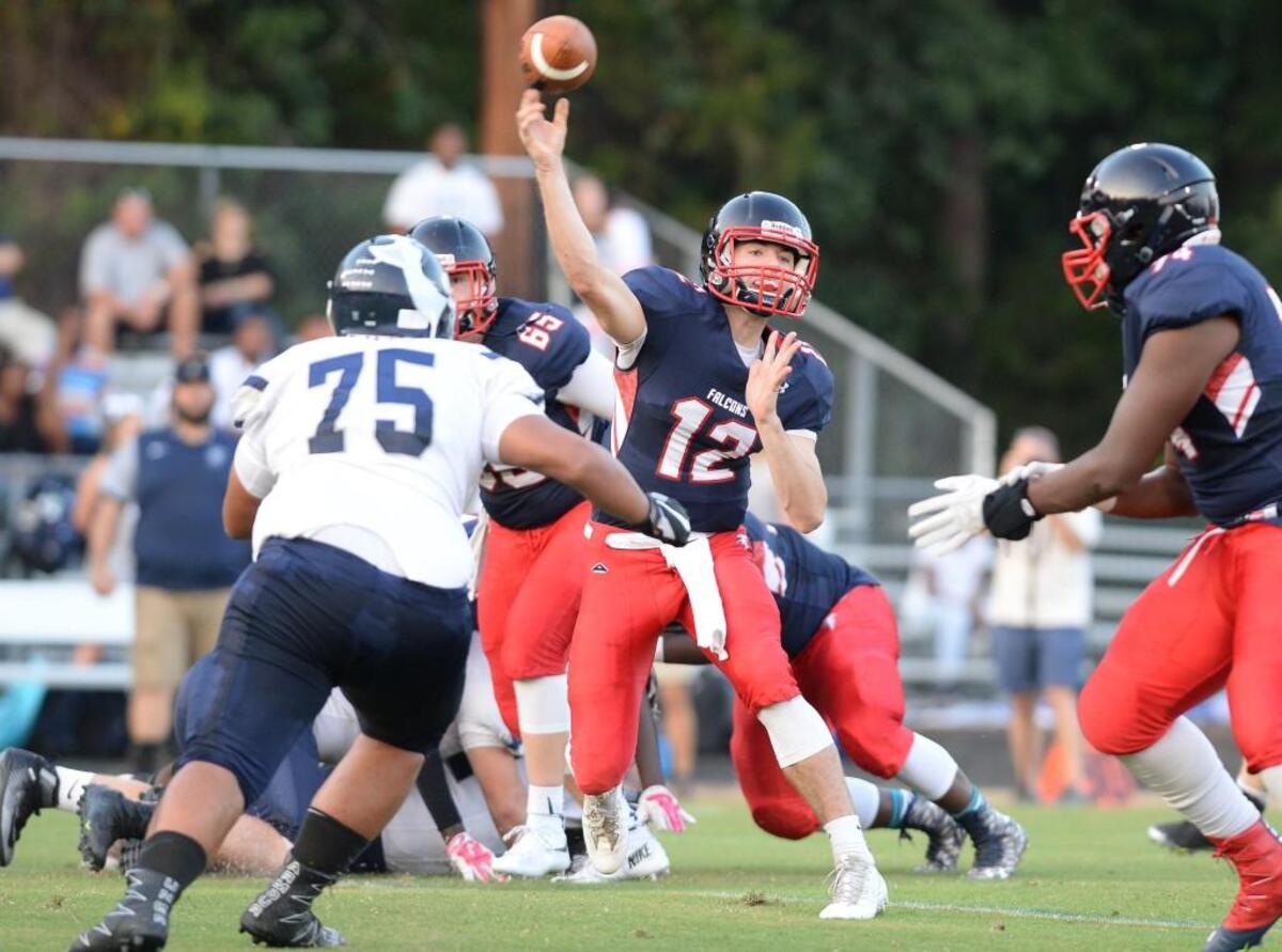 Quarterback Ben Miller (12) of Jordan throws a pass under pressure from Maui Garchitorena (75) of Heritage. The Jordan Falcons played the Heritage Huskies in a football game that took place in Durham, N.C. on Friday, September 9, 2016. Heritage won 32-17.